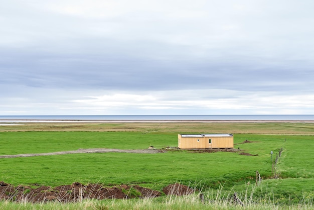 Prefabricated yellow house on a meadow in southern Iceland with the sea in the background