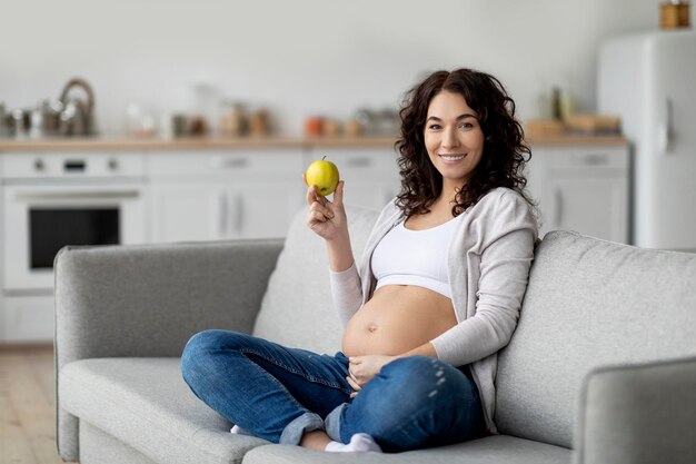 pregnancy diet smiling pregnant woman holding green apple and touching her belly