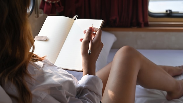 Pregnancy female writing on notebook in recreational vehicle.