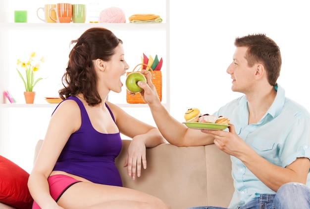 pregnancy and healthy eating concept - happy expecting parents at home