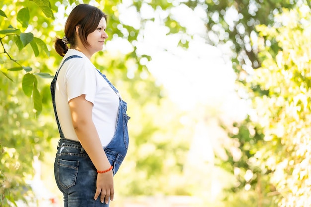 妊娠、愛、人々と期待の概念-緑の自然の背景上の幸せな妊娠中の女性