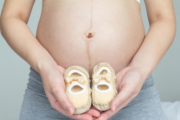 Foto concetto di amore per la gravidanza giovane incinta e le sue scarpe per bambini