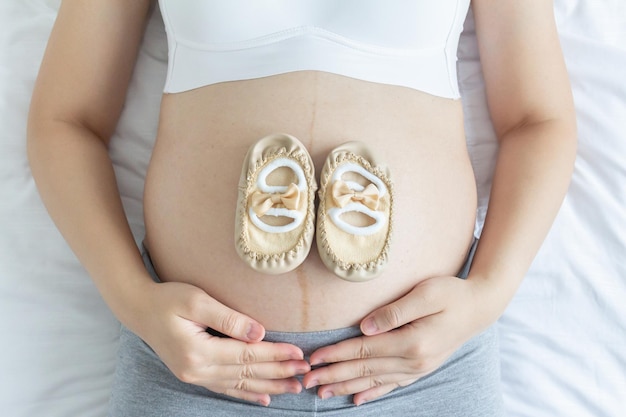 Foto concetto di amore per la gravidanza giovane incinta e le sue scarpe per bambini