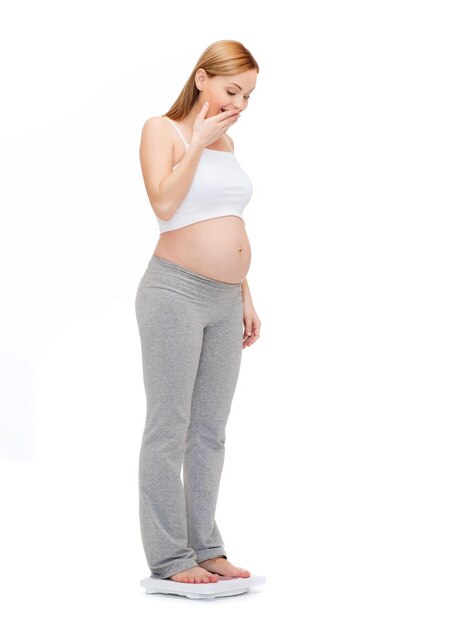 妊娠、母性、幸福の概念-自分自身に重みを付けている驚いた妊娠中の女性