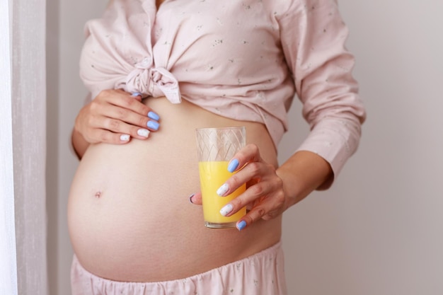 임신한 사람들과 휴식 개념 행복한 임산부는 집에서 오렌지 주스를 마시거나 들고 있다