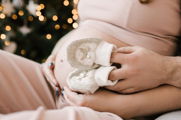 임신 사진 촬영 남성과 여성의 손과 아기 옷