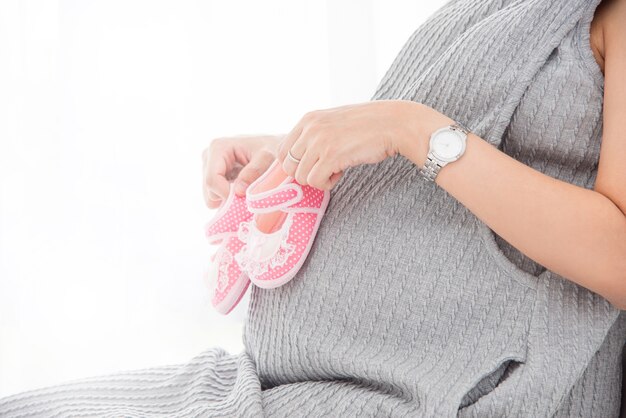 La gravidanza mise delle piccole scarpe rosa sulla pancia