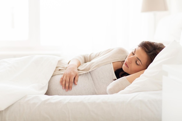 pregnancy, rest, people and expectation concept - happy pregnant woman sleeping in bed at home