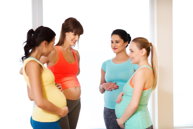 妊娠、スポーツ、フィットネス、人々、健康的なライフ スタイル コンセプト - ジムで話している幸せな妊娠中の女性のグループ