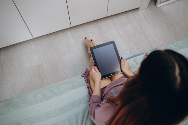 妊娠技術の人々と期待の概念は、自宅のベッドでタブレットPCコンピューターを持つ妊婦のクローズアップ