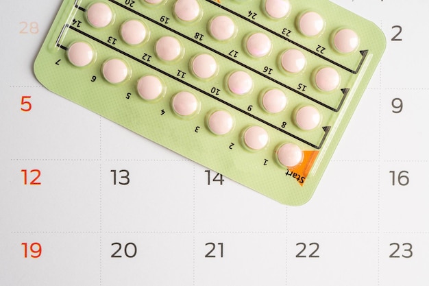 Photo pregnancy test and birth control pills on calendar contraception health and medicine