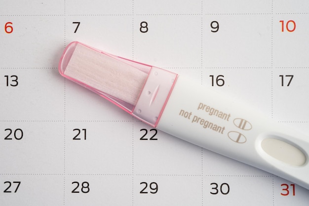 Photo pregnancy test and birth control pills on calendar contraception health and medicine