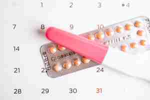 Photo pregnancy test and birth control pills on calendar contraception health and medicine