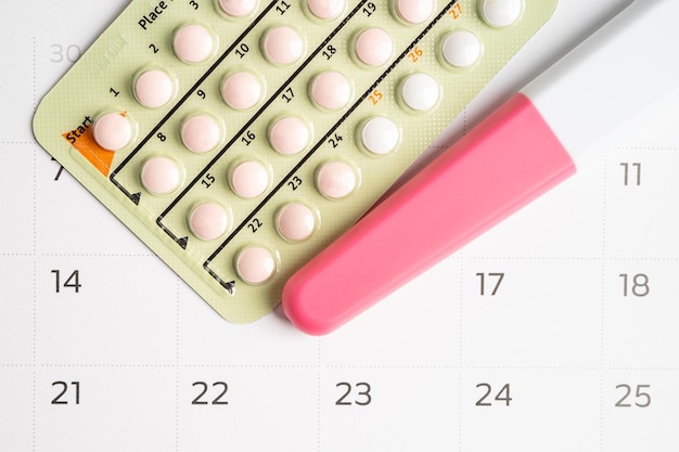 Photo pregnancy test and birth control pills on calendar contraception health and medicine