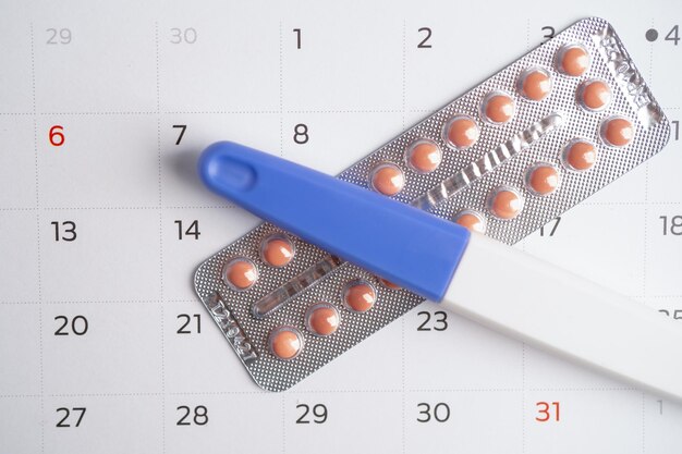 Photo pregnancy test and birth control pills on calendar contraception health and medicine