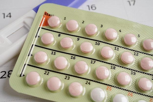 Pregnancy test with birth control pills and condom for female on calendar ovulation day