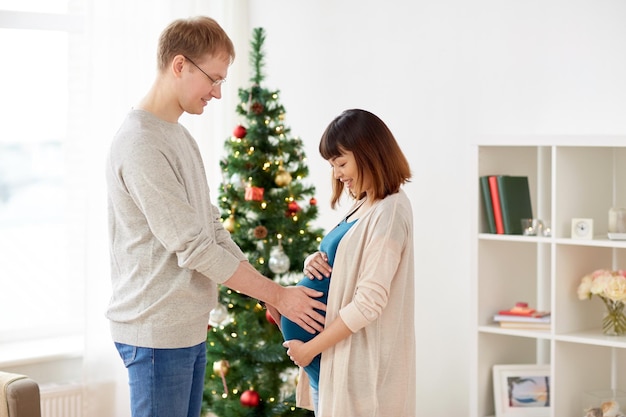 임신, 겨울 휴일 및 사람 개념 - 크리스마스에 집에 남편과 함께 행복한 임산부