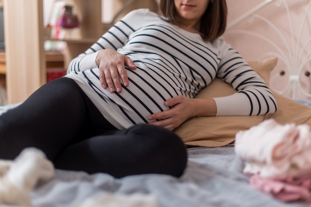 写真 妊娠中の女性が自宅のベッドに座って