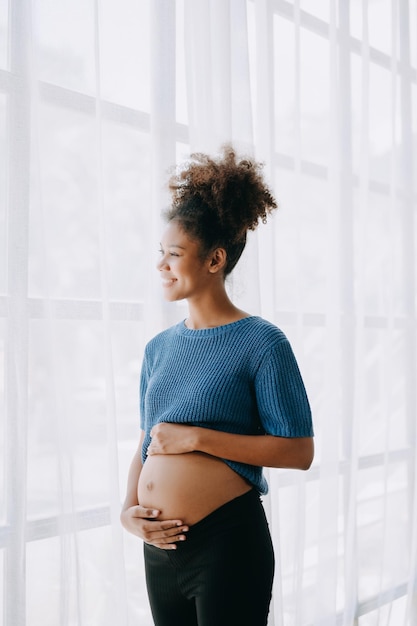 家の窓の白い背景の空間に妊娠しているアフリカ系アメリカ人女性