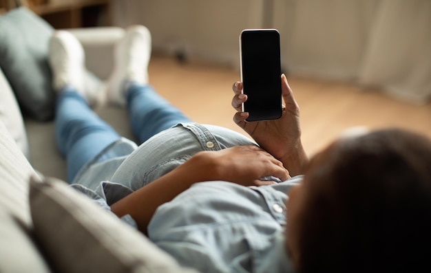 Pregnant african female using phone with blank screen at home