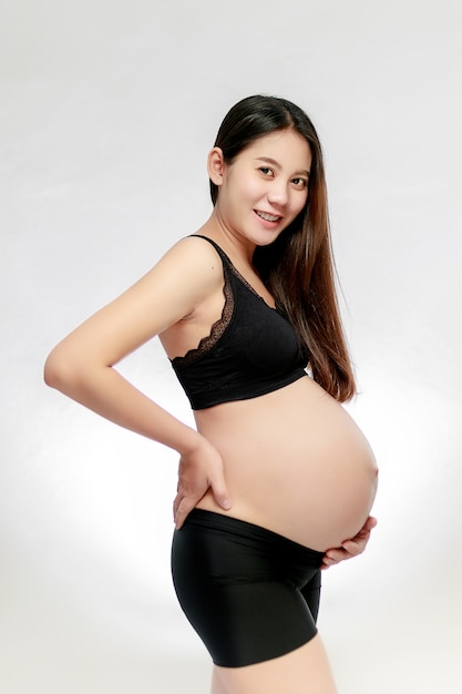 Pregnant asian woman hands holding on belly making a take care and love symbol on white background. Happy pregnant woman concept.