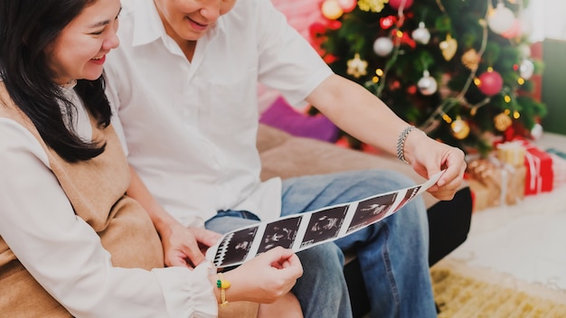 Pregnant Asian woman looking at ultrasound pictures with husband