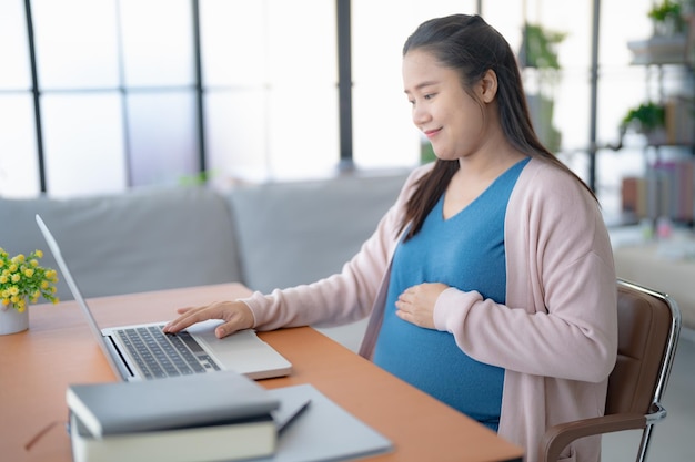 pregnant asian woman using laptop at home pregnant businesswoman typing on laptop working on remote project in home office pregnancy