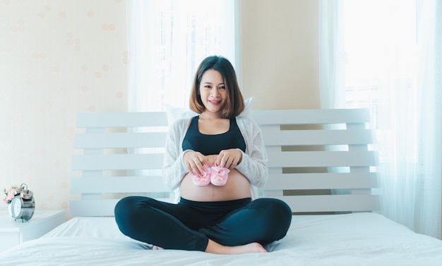 Pregnant Asian women are having fun with baby shoes.