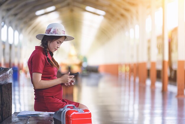 列車で旅行中に携帯電話を使用して妊娠中の美しい女性。退屈の概念。