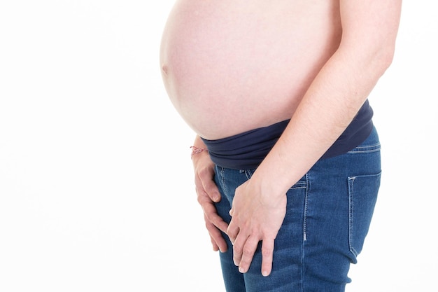 Вид на беременный живот женщины в джинсовых брюках