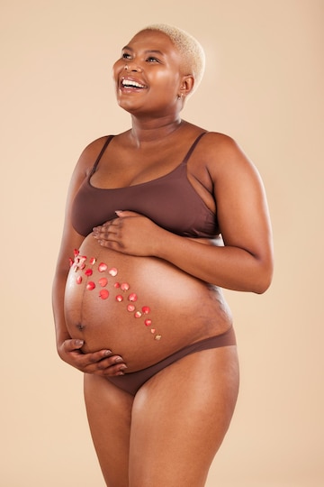 Premium Photo  Pregnant black woman and smile with flowers on belly in  studio for body baby wellness and ivf healthcare mother pregnancy and  floral plants on stomach with happiness beauty or