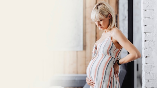 Pregnant blond-haired woman in a living room