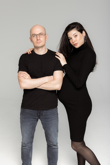 Pregnant brunette girl in a black dress with a throat and a man in a Tshirt and jeans