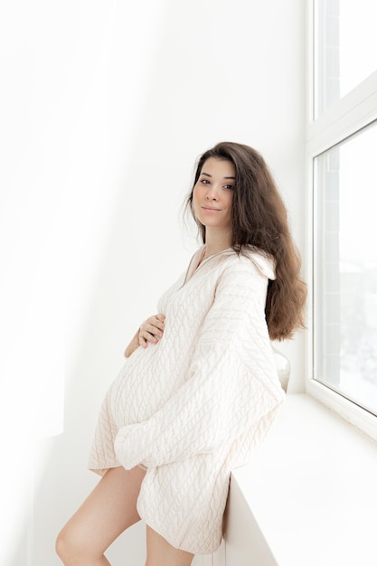 Pregnant brunette girl in an oversized knitted sweater