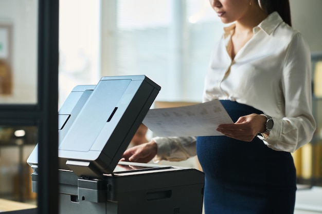 Pregnant businesswoman using copier