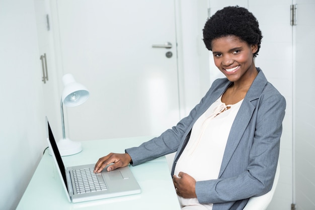 Pregnant businesswoman working on laptop in office