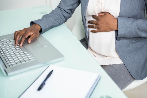 Pregnant businesswoman working on laptop in office