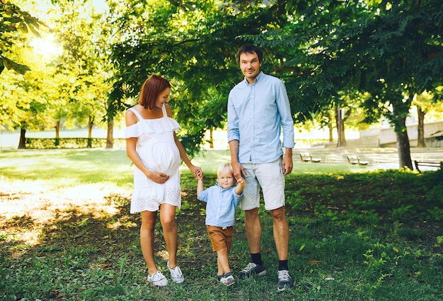 Pregnant family in expectation of baby Husband and pregnant wife with toddler kid in summer nature