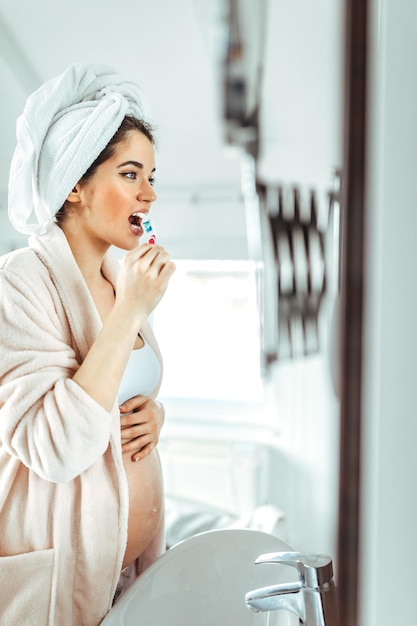 Pregnant female brushing teeth at home