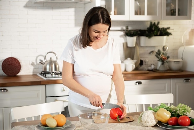 La ragazza incinta cucina in cucina a casa