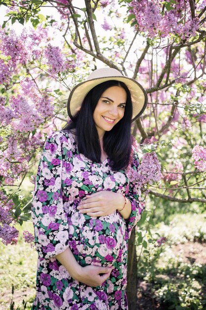 A pregnant girl in a dress near the sakura in the garden