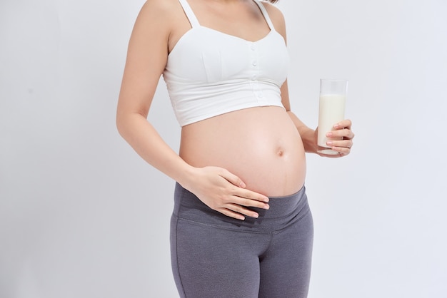 Pregnant girl drinks milk on a white background