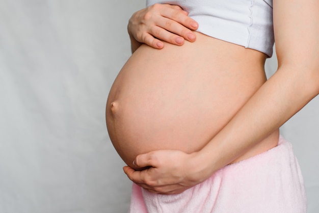 Pregnant girl gently hugging her belly