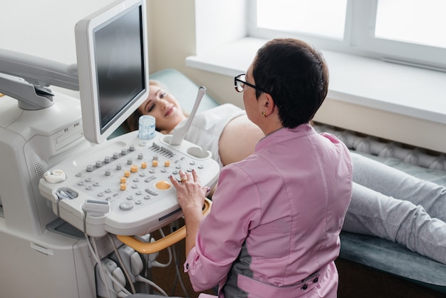 妊娠中の女の子が診療所で腹部の超音波検査を受けます。健康診断