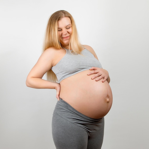회색 배경에 임신한 여자 큰 배 허리 통증