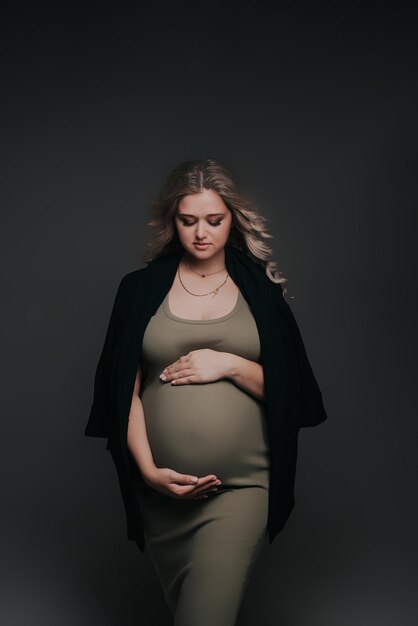 Pregnant girl in a green dress on a gray background