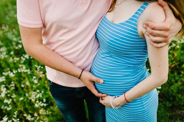 Ragazza incinta e suo marito da abbracciare, tenere le mani sullo stomaco. avvicinamento. stomaco. la metà superiore. mezza lunghezza