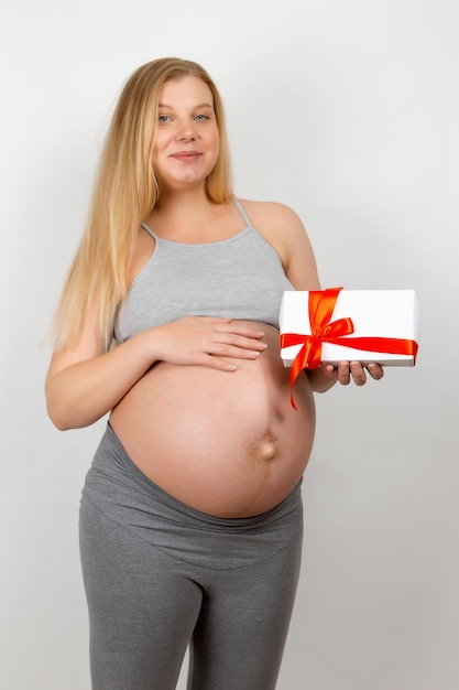 A pregnant girl holds a gift The birth of a remenka is the best gift