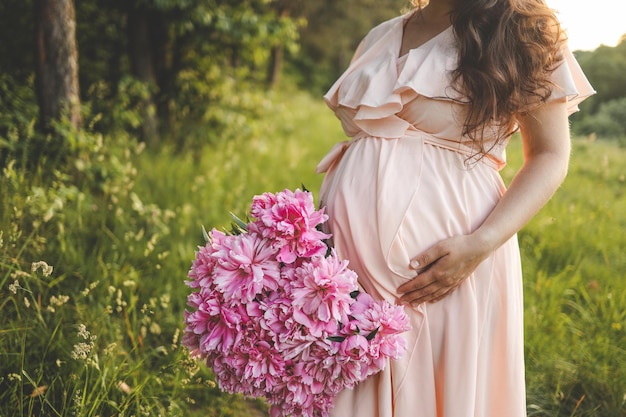 写真 牡丹の花束を持つ自然の中で妊娠中の女の子