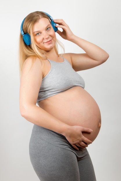 Pregnant woman listens to music on headphones, gently caresses her belly  thinking about her baby, enjoying her pregnancy 24697149 Stock Photo at  Vecteezy